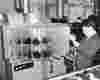 a technician in a suit inspects a piece of equipment is a shoe factory