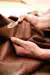 male hands stretch a piece of brown leather