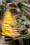 close-up of several pairs of sandals on a rack in a shoe factory, awaiting sole attachment