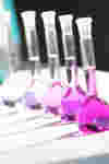 a row of small laboratory flasks containing pink liquid